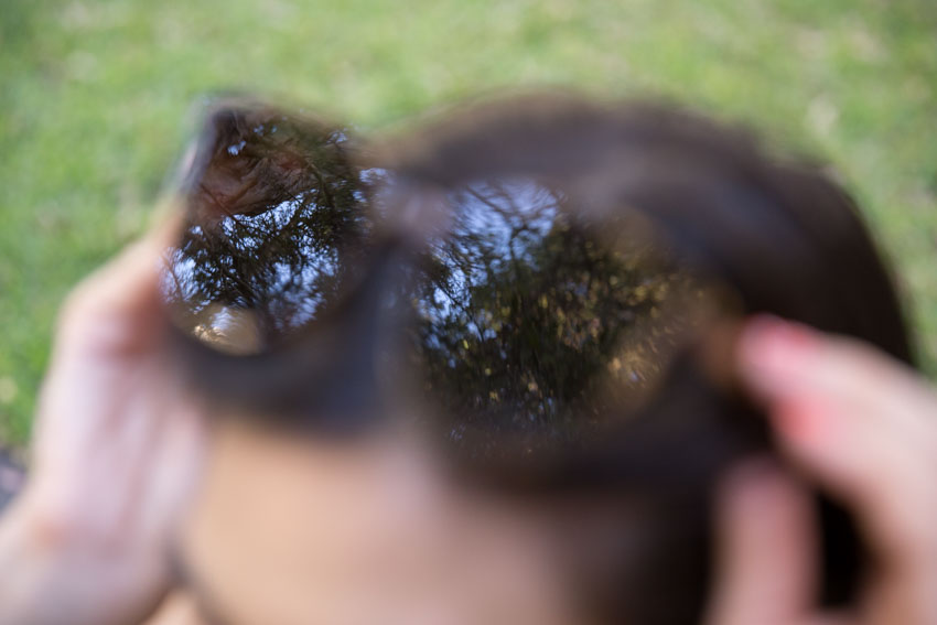 Close up of my sunglasses on my head, with the reflection of trees in focus and the sunglasses out of focus