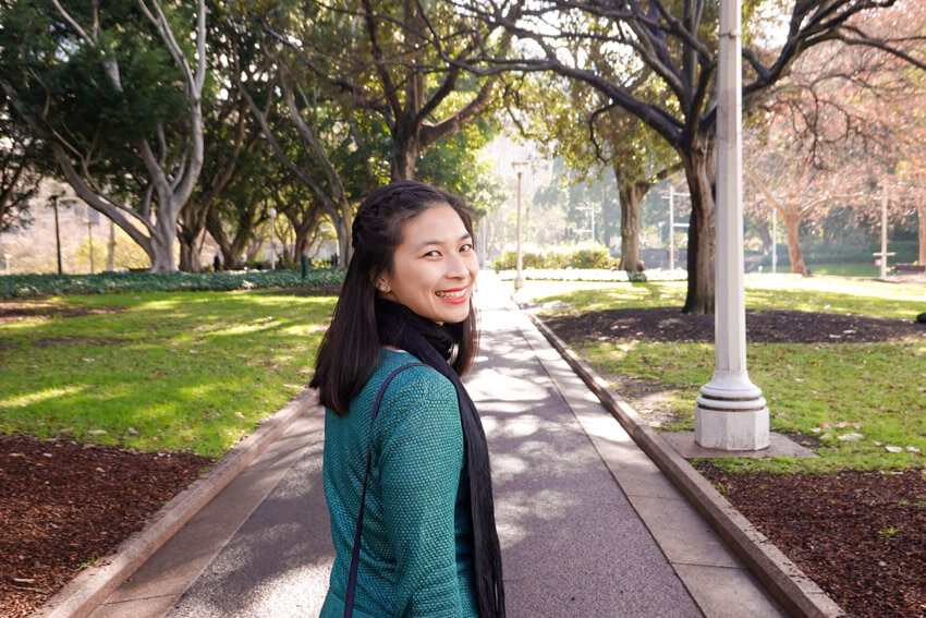 The same woman from the previous photo, wearing the same clothes and in the same setting. She has her body facing away from the camera but is looking back.