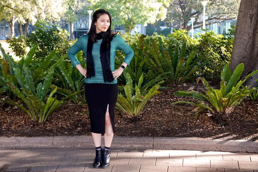 The same woman from the previous photo, wearing the same clothes and in the same setting. She has her hands on her hips and is facing the camera