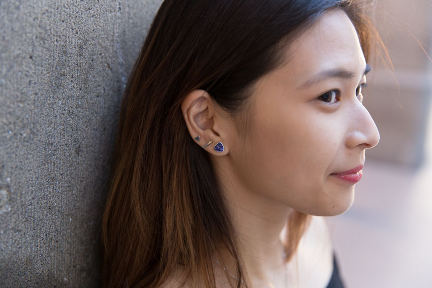 Close up of my earrings, one purple stud, one silver bar stud, and one silver triangle stud