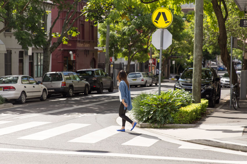 Side view of me starting to walk on a pedestrian crossing, with a yellow pedestrian crossing sign nearby