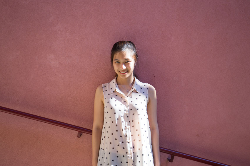 Medium shot of me against a deep pink-ish wall with a dark red railing