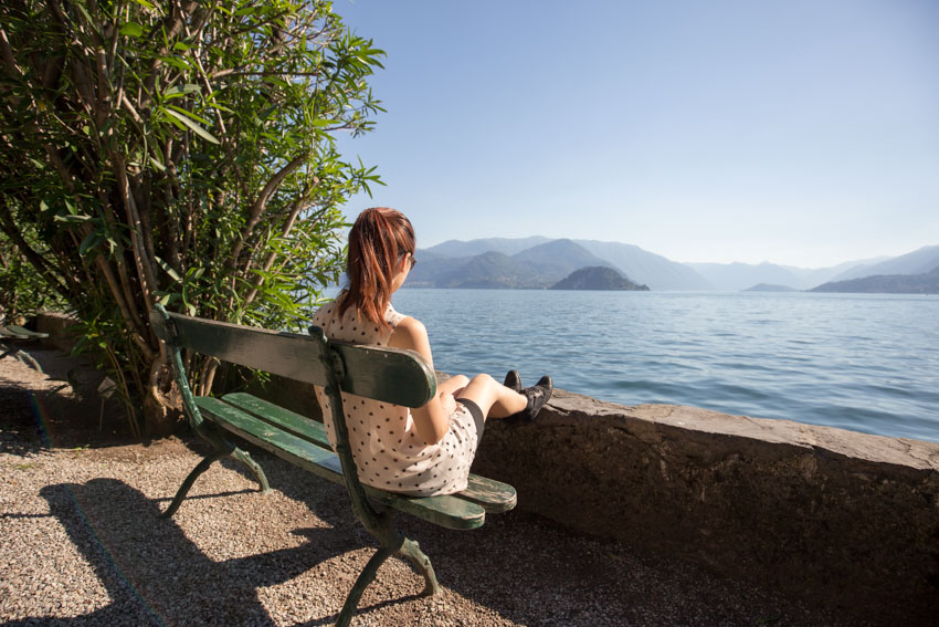 Me sitting on a green bench with my back to the camera and looking out on Lake Como