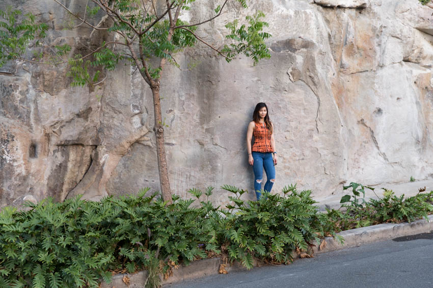 A far shot of me leaning against the rock with some foliage in the foreground