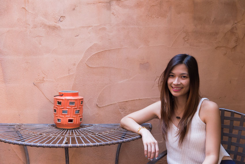 Sitting in a courtyard with my arm resting on a table and an orange lantern on the table