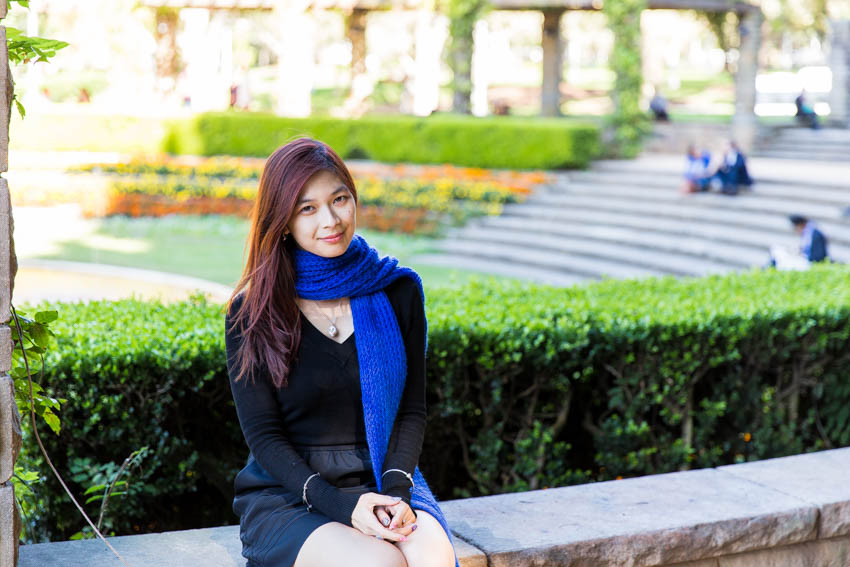 Medium shot of me sitting on a stone ledge with some flowers and steps in the distance