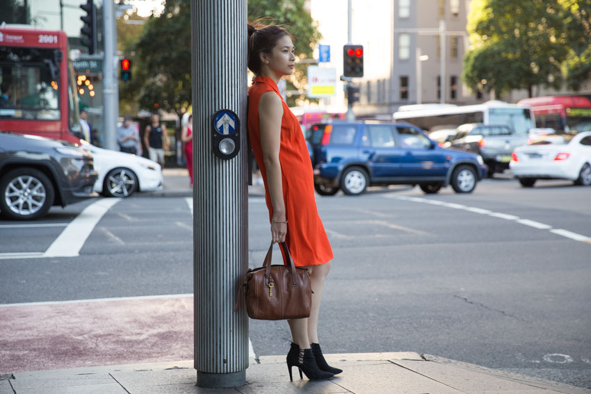 Me slouching a little as I lean on a pole with my bag in my hand