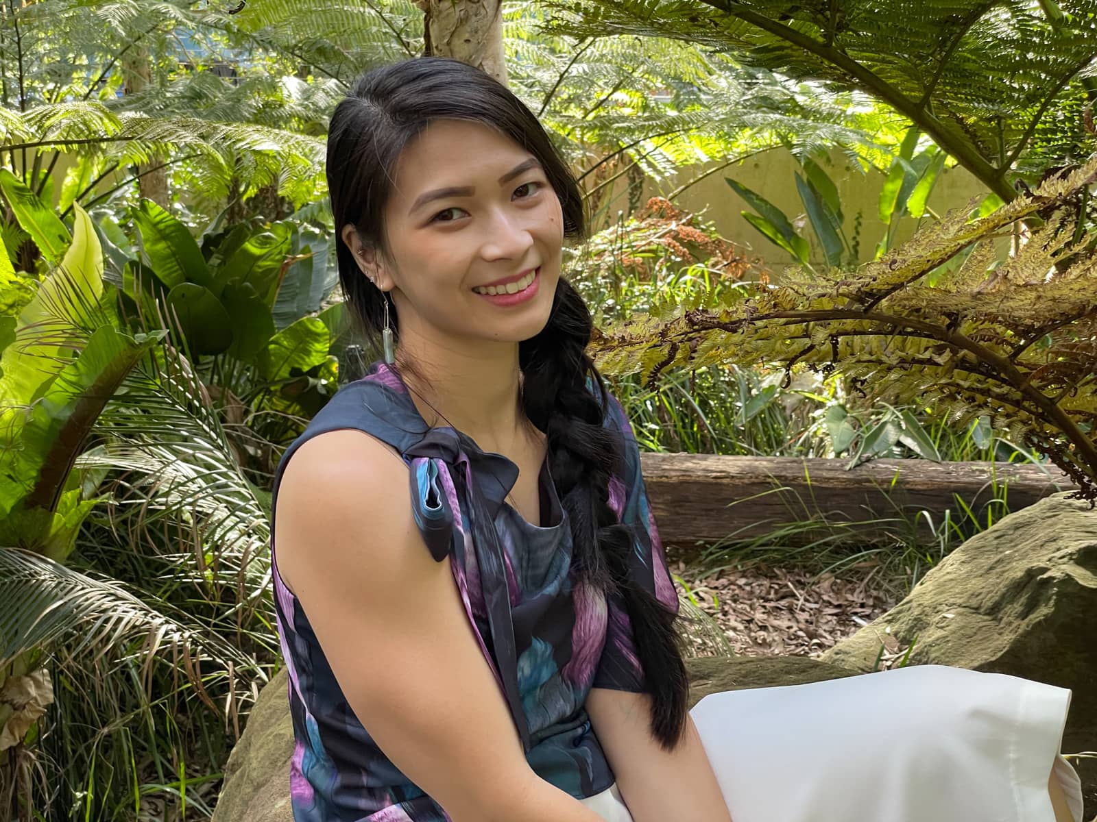 A close-up medium shot of the same woman in earlier photos on this page, in the same patterned top and sitting on a rock.