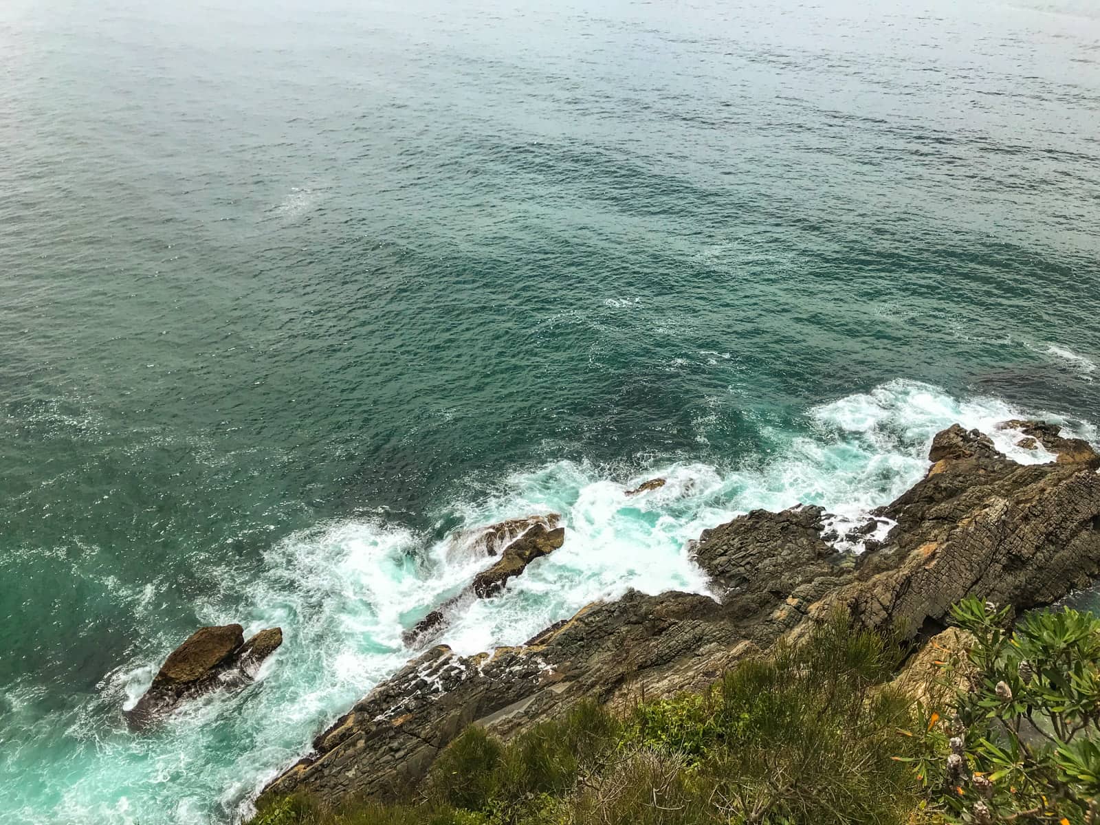 A rock face, seen from above, at the edge of the sea, with the sea taking up most of the frame.