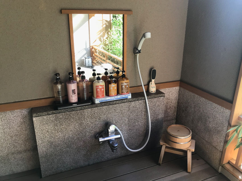 Some showerheads and shampoo, conditioner and body soap on a stone shelf