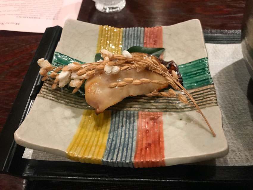 Closeup of grilled Spanish mackerel with a stick of popped rice pieces