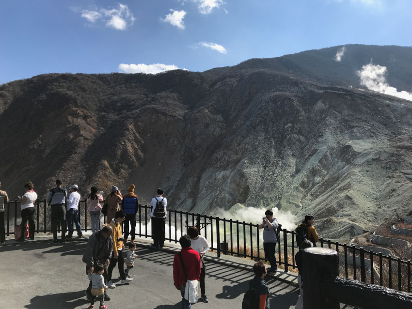 A handful of tourists around a railing with the sulphur fumes in the background