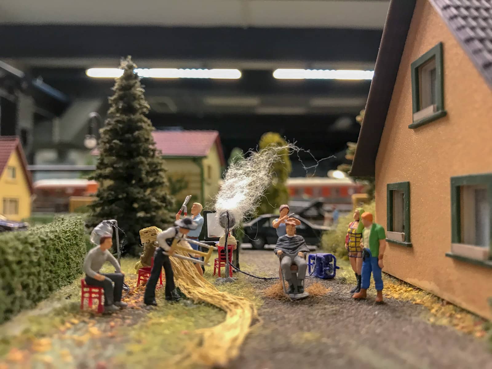 Miniature figurines in a scene – someone appears to be getting their hair cut while other figurines show housework or are just standing around.