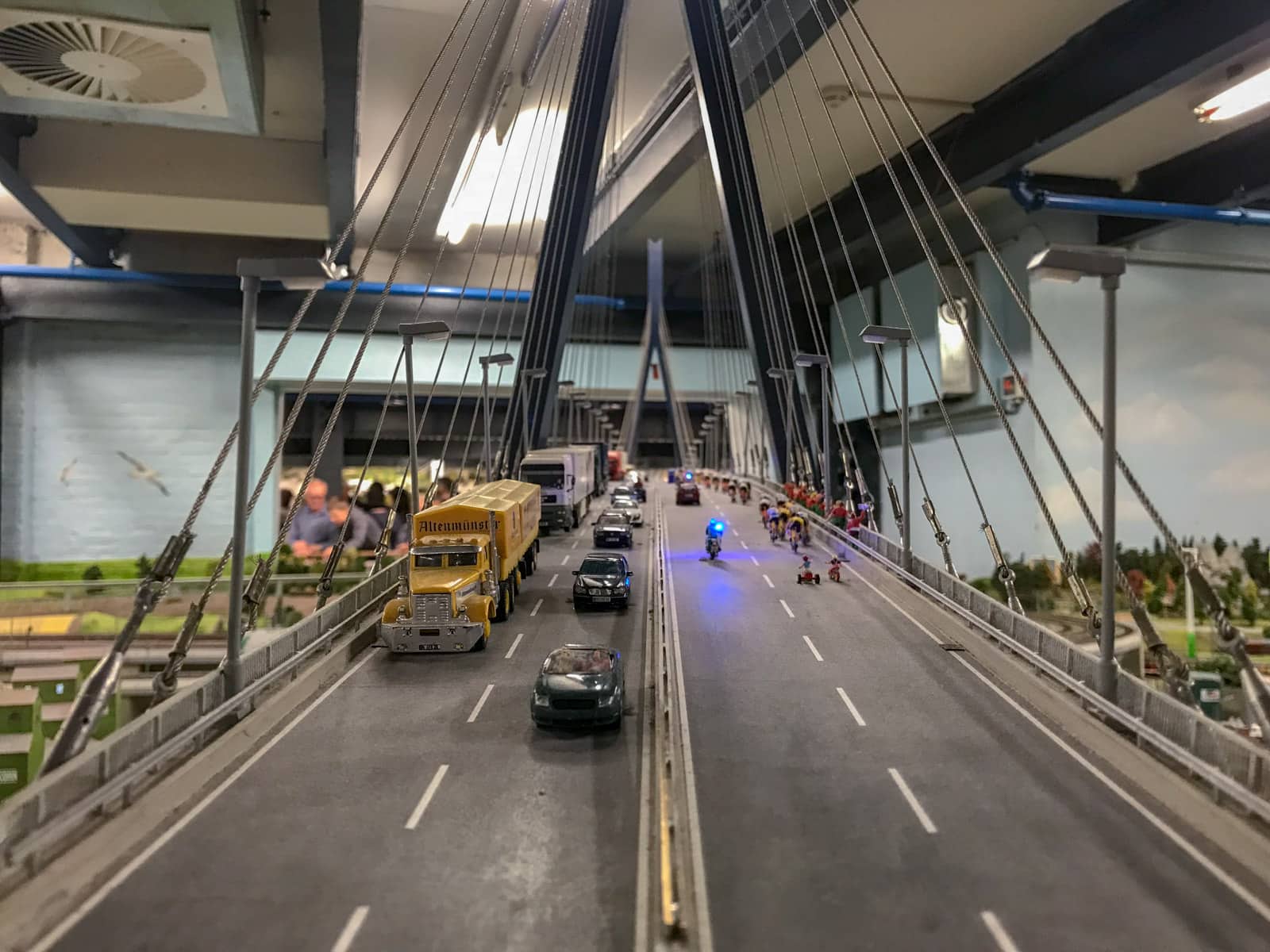 A close-up view of a bridge with traffic running in both directions, that is part of a miniature model railway.