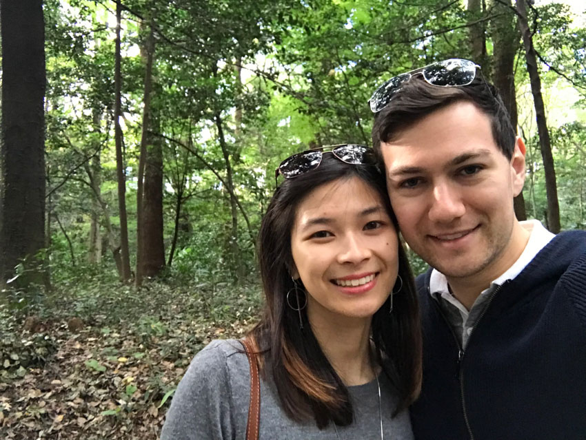 Me and Nick with sunglasses on top of our heads, holding each other close, with some green trees in the background