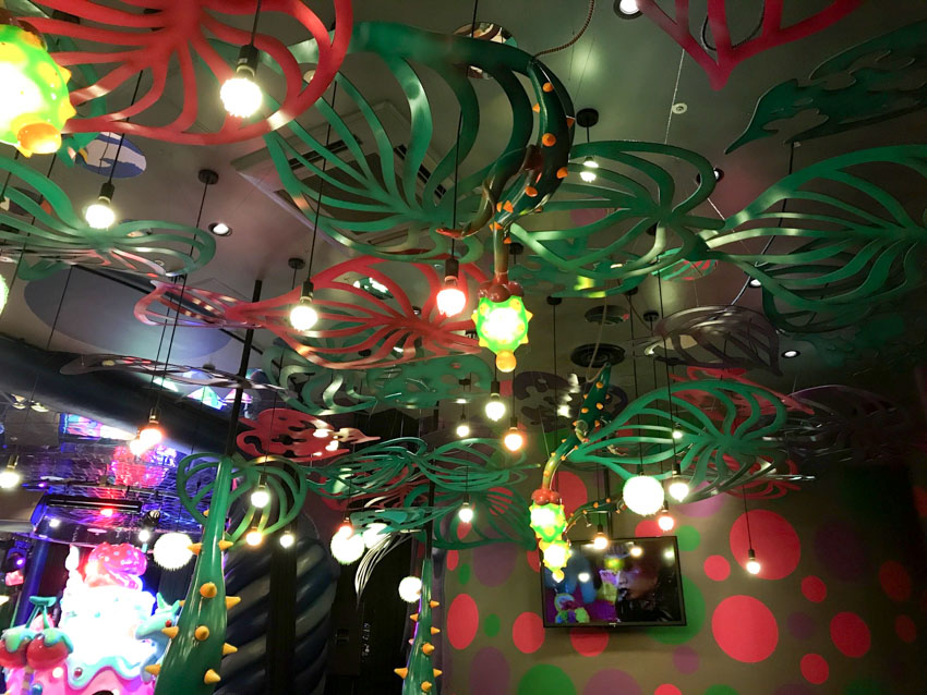 Red and green leaf-shaped panels hanging from the ceiling amongst some lights