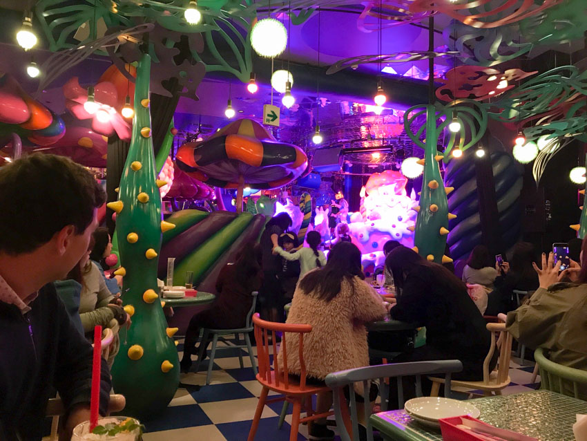 Restaurant setting with a black-and-white checkered floor, and large decor resembling trees