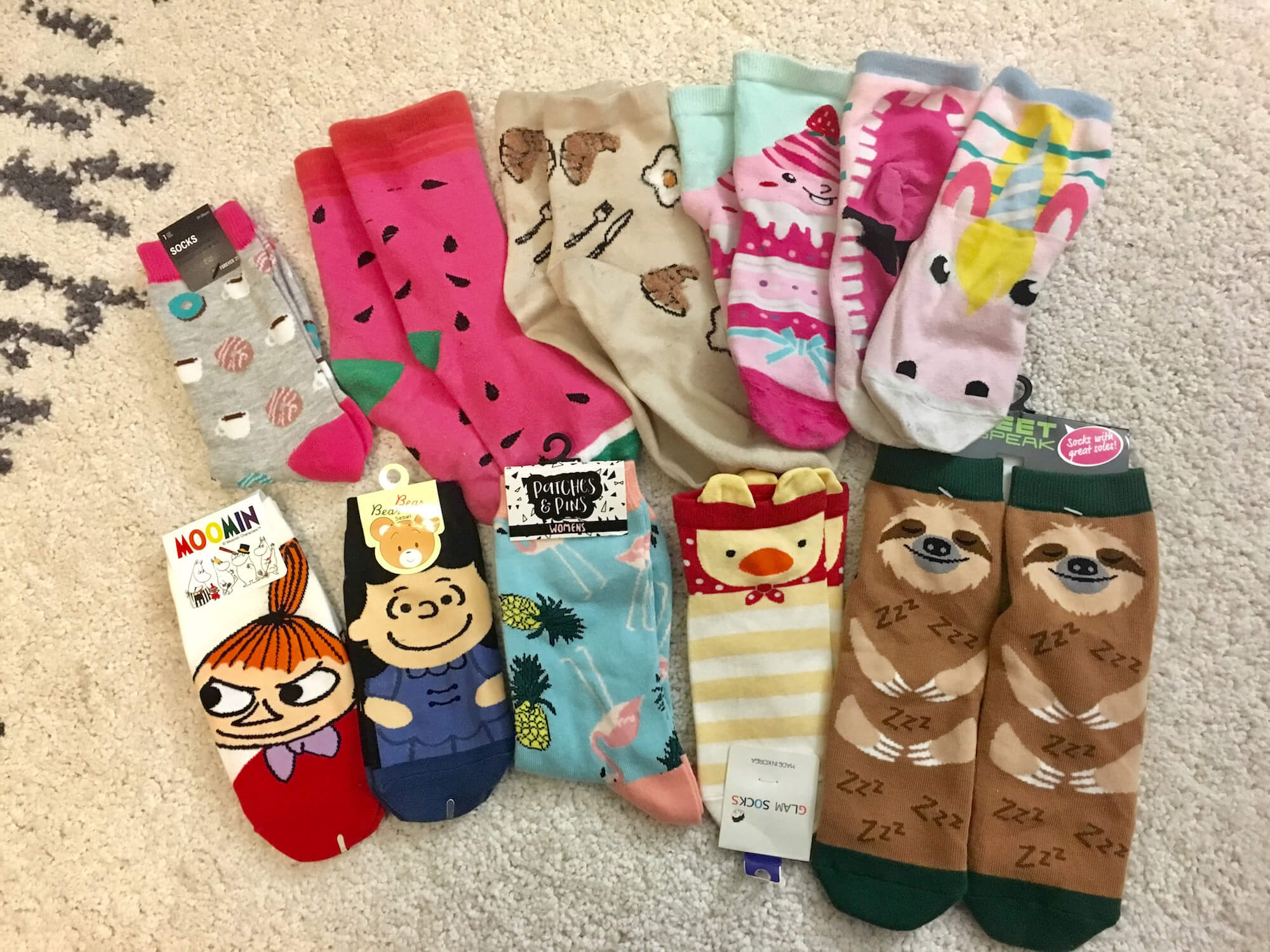 Ten pairs of colourful, patterned socks laid out on carpet