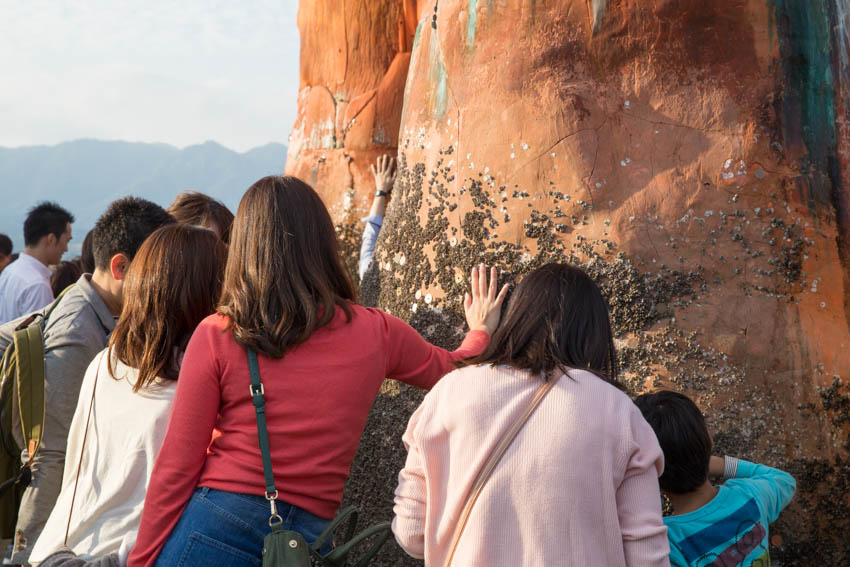 People reaching out to touch the shrine