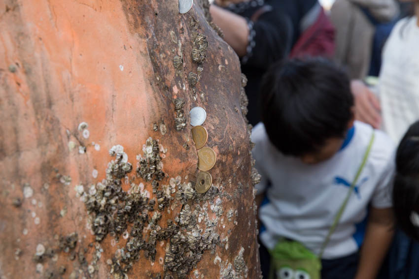 Close up of Japanese coins stuck into the pillar of the gate