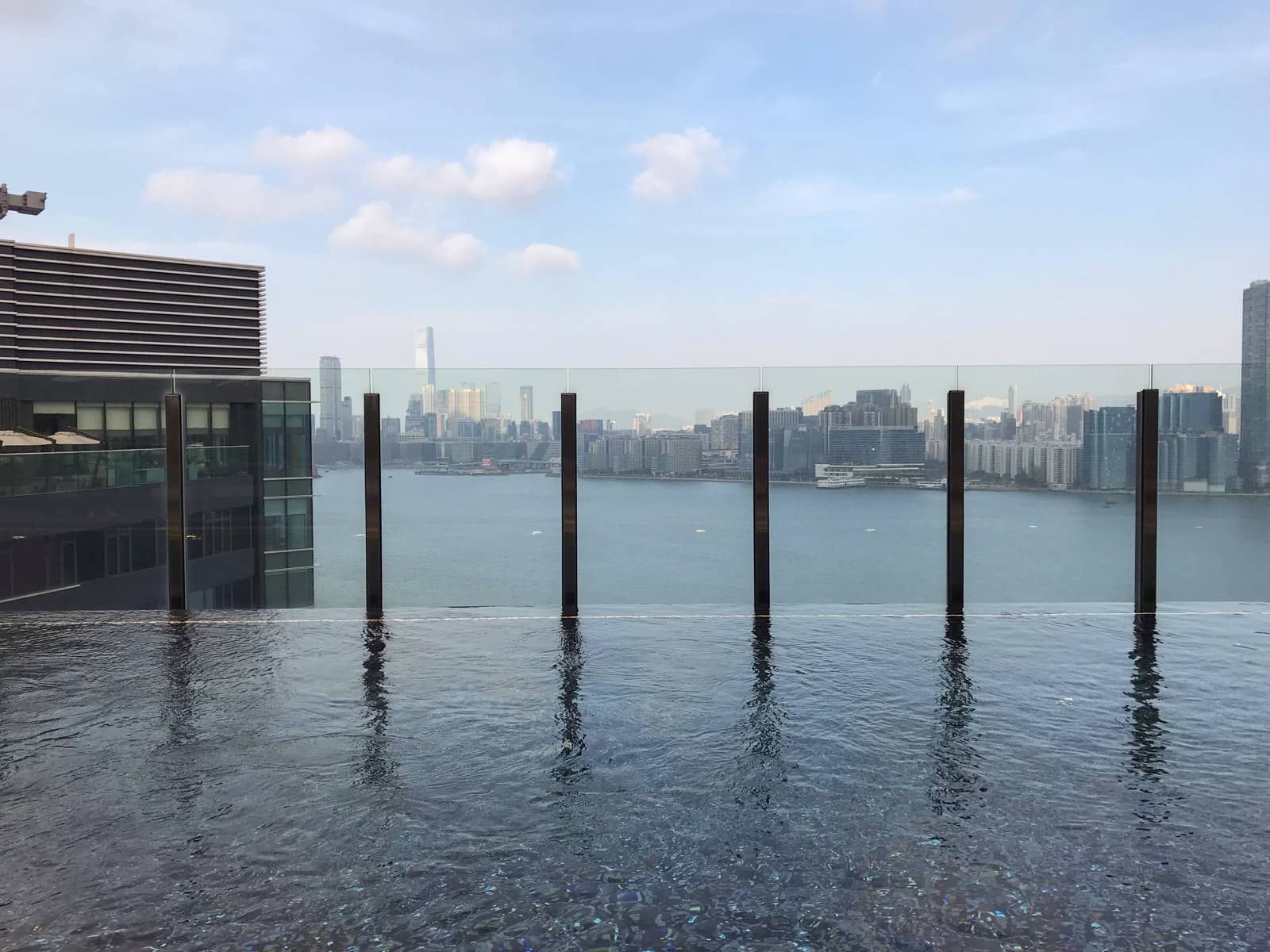 The view of an infinity pool from the water side, showing a view of Hong Kong through the glass at the end of the pool