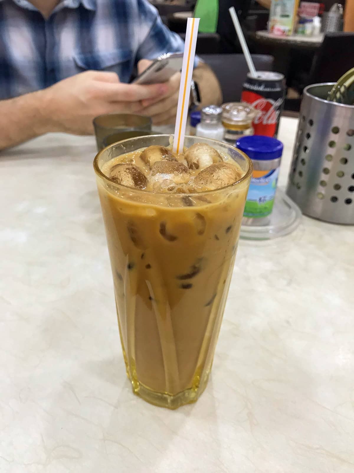 A tall glass of Hong Kong milk tea, which is iced and has a tan brown colour to it