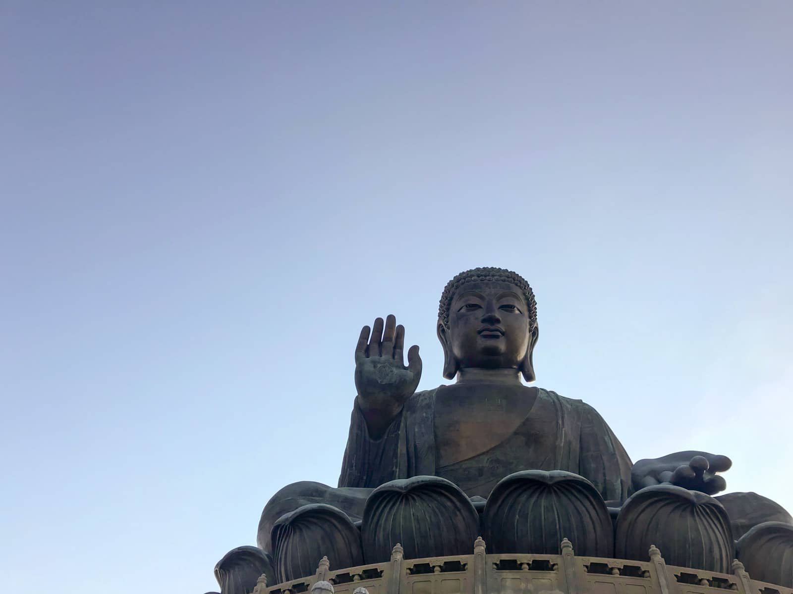 A very large Buddha statue from a low angle. The sky is clear and blue but it is dusk