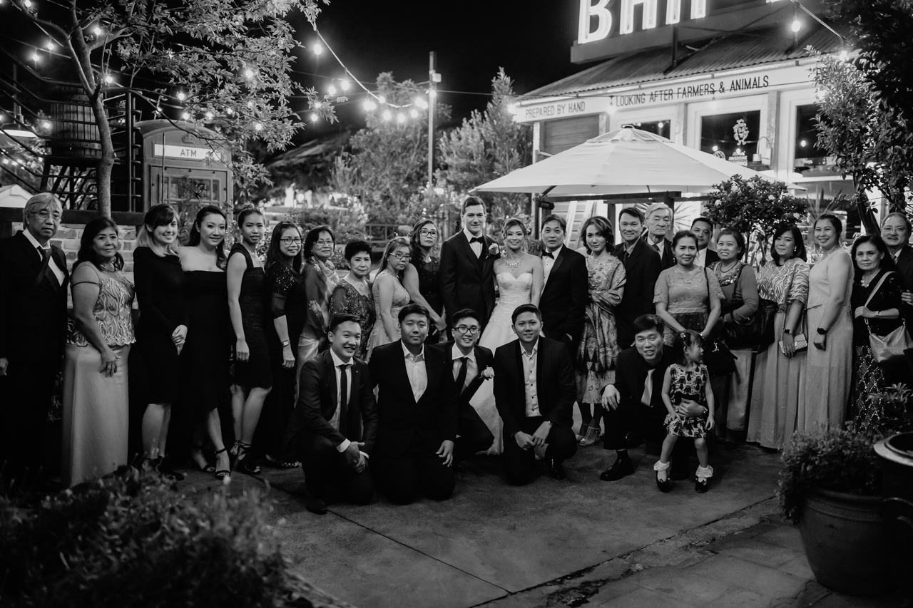 A man and woman in wedding attire, with a large group of family