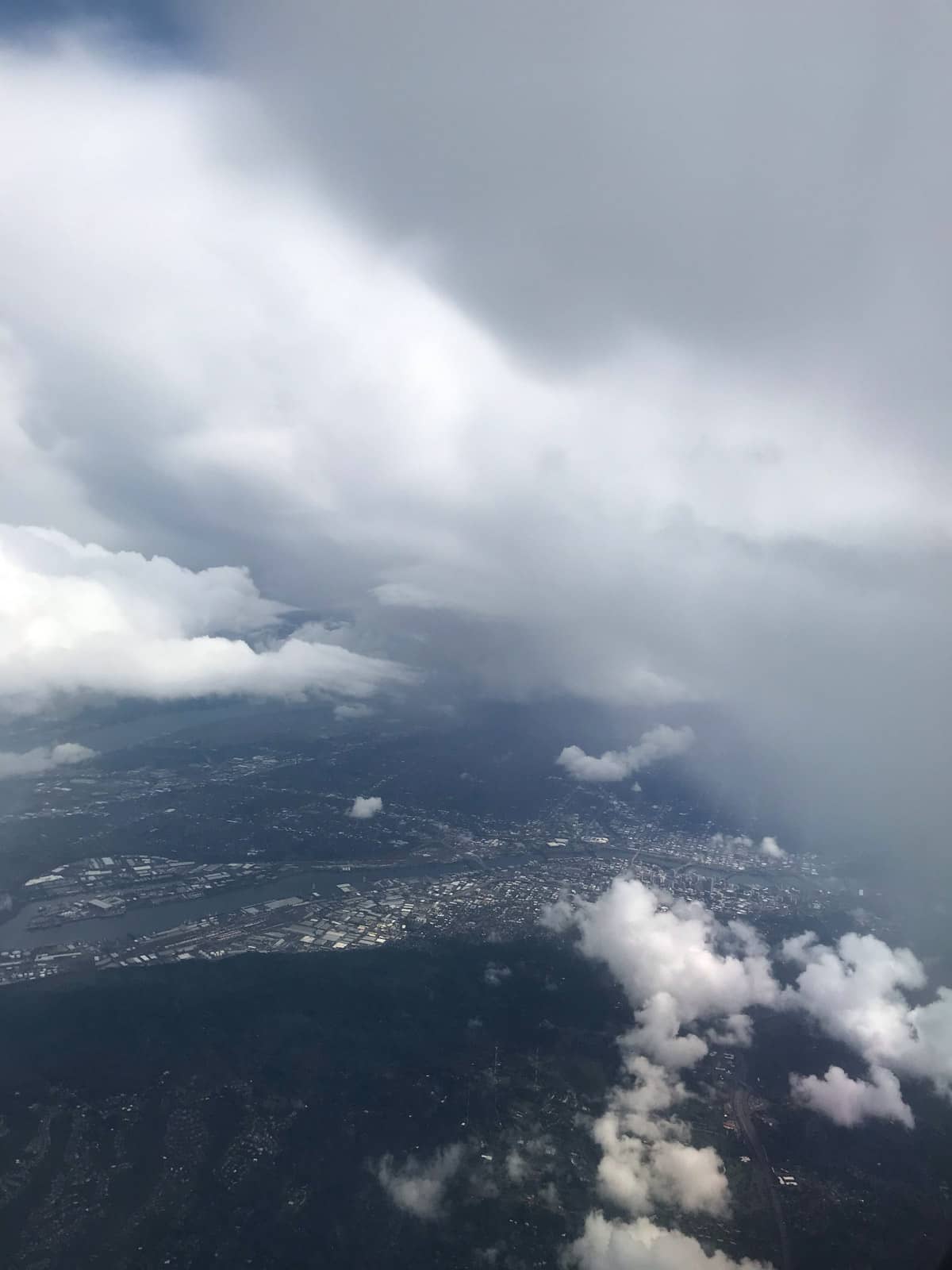 An aerial view of a city as seen from an airplane. Many clouds obscure the view