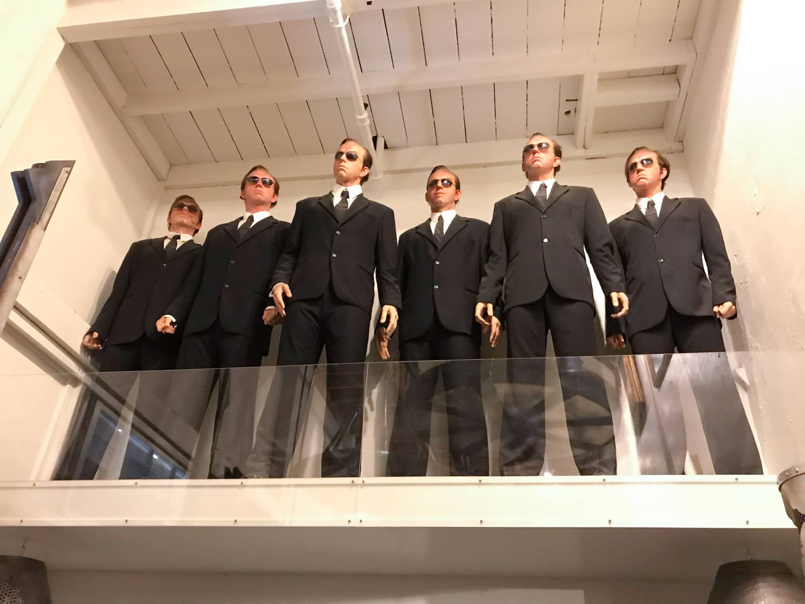 A prop of six men in suits and dark sunglasses made to resemble the same character