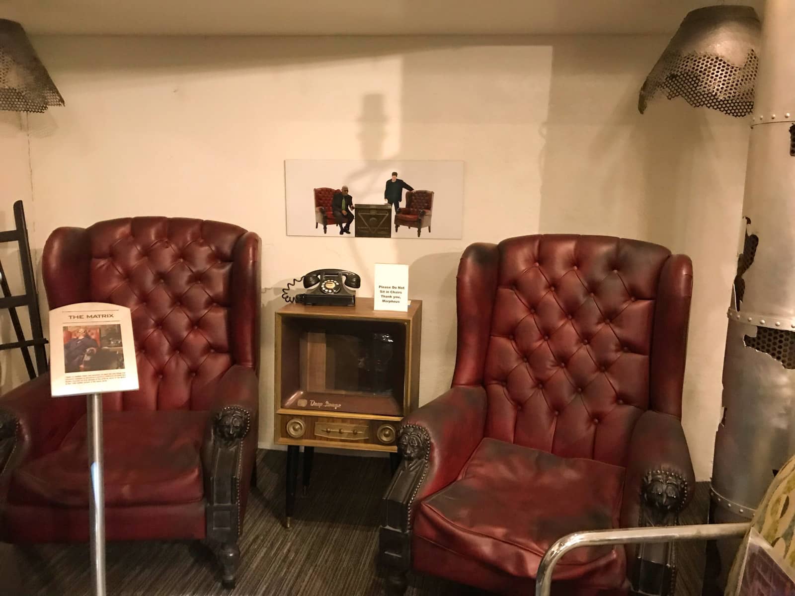 Two dark red leather chairs shown on display signage to be famous for their use the film The Matrix