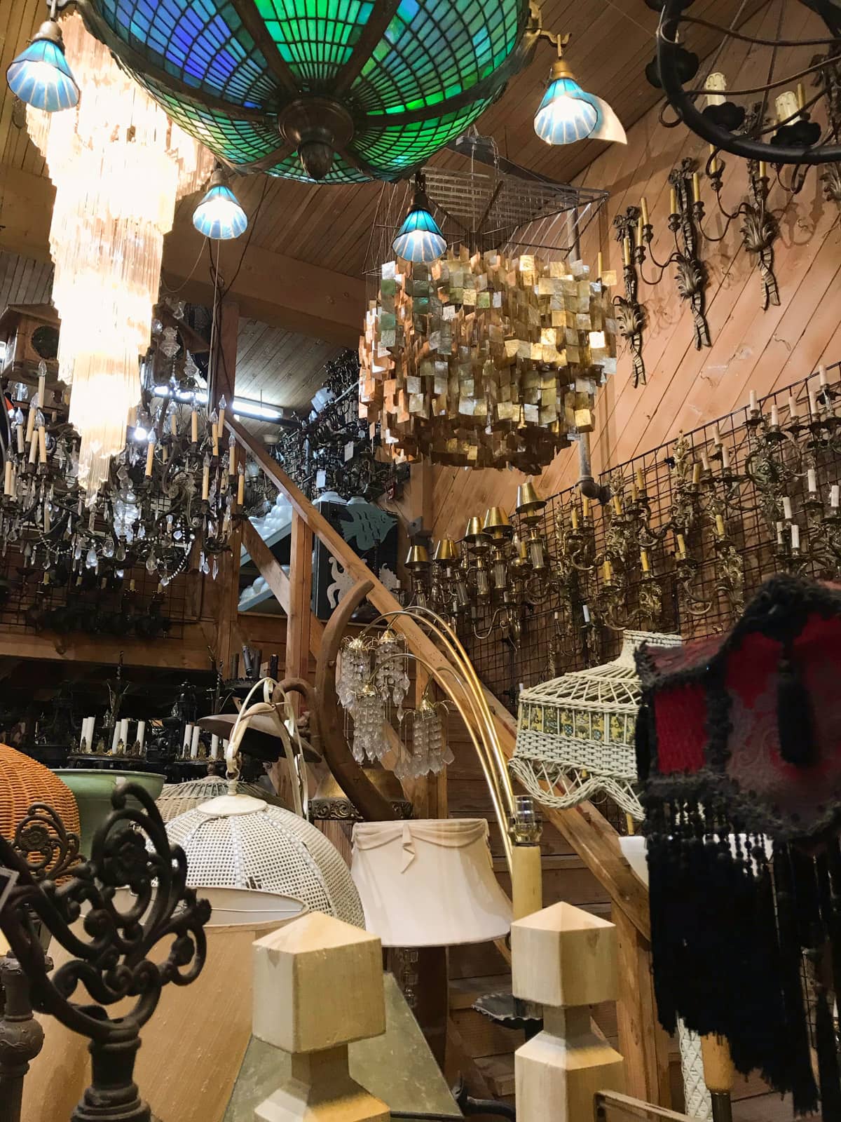 The inside of a props warehouse with many lanterns, chandeliers and other lighting.