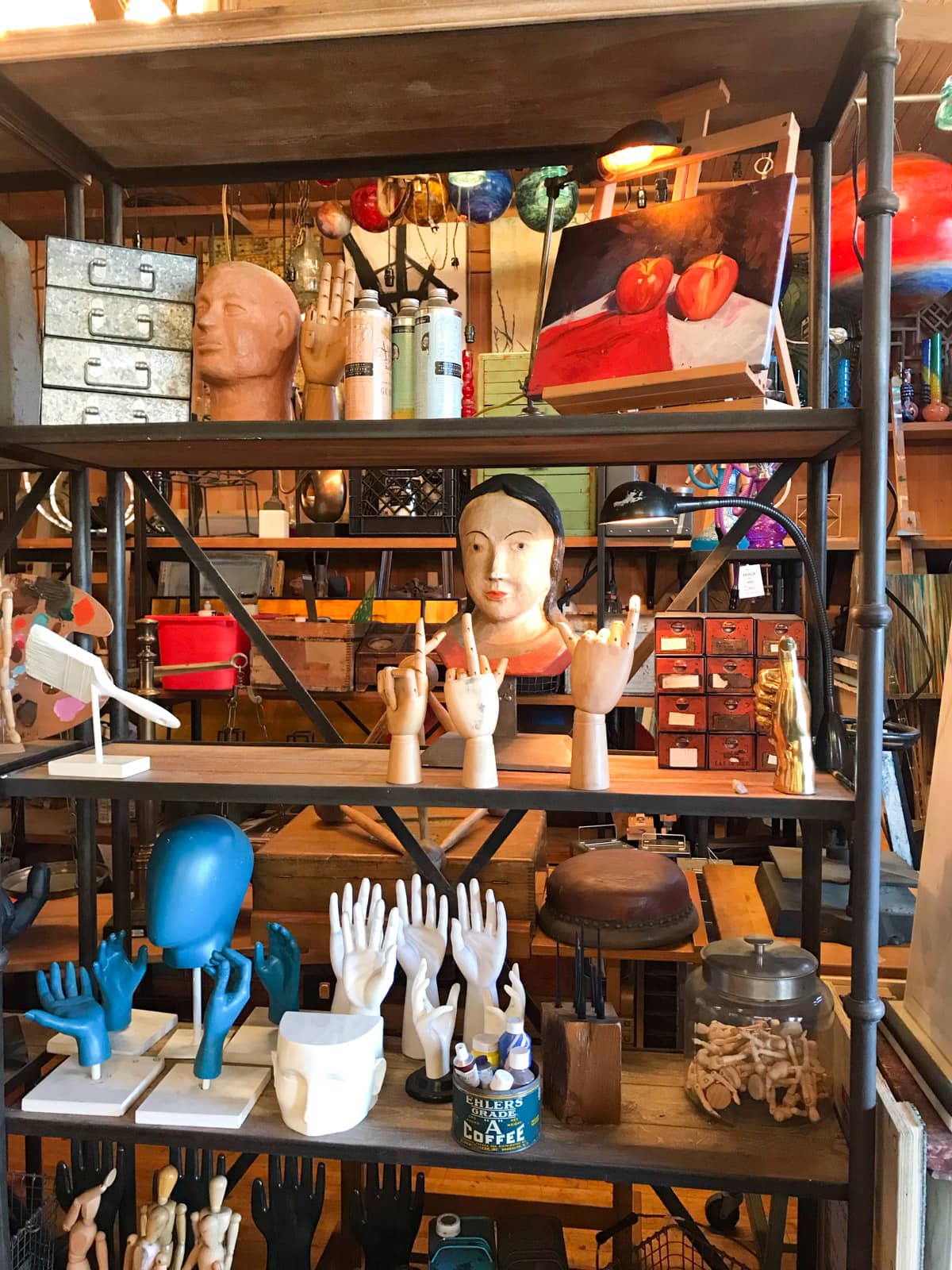 A shelf of many props, most of them being models of hands and heads. Shelves in the background are full as well.