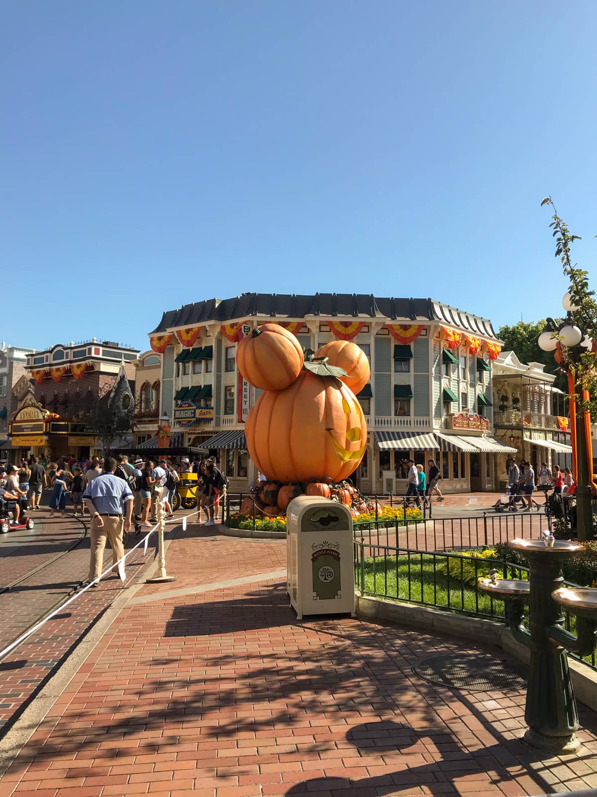 A view inside a Disneyland theme park, where a large statue of Mickey’s head styled like a carved pumpkin is in the centre of the frame