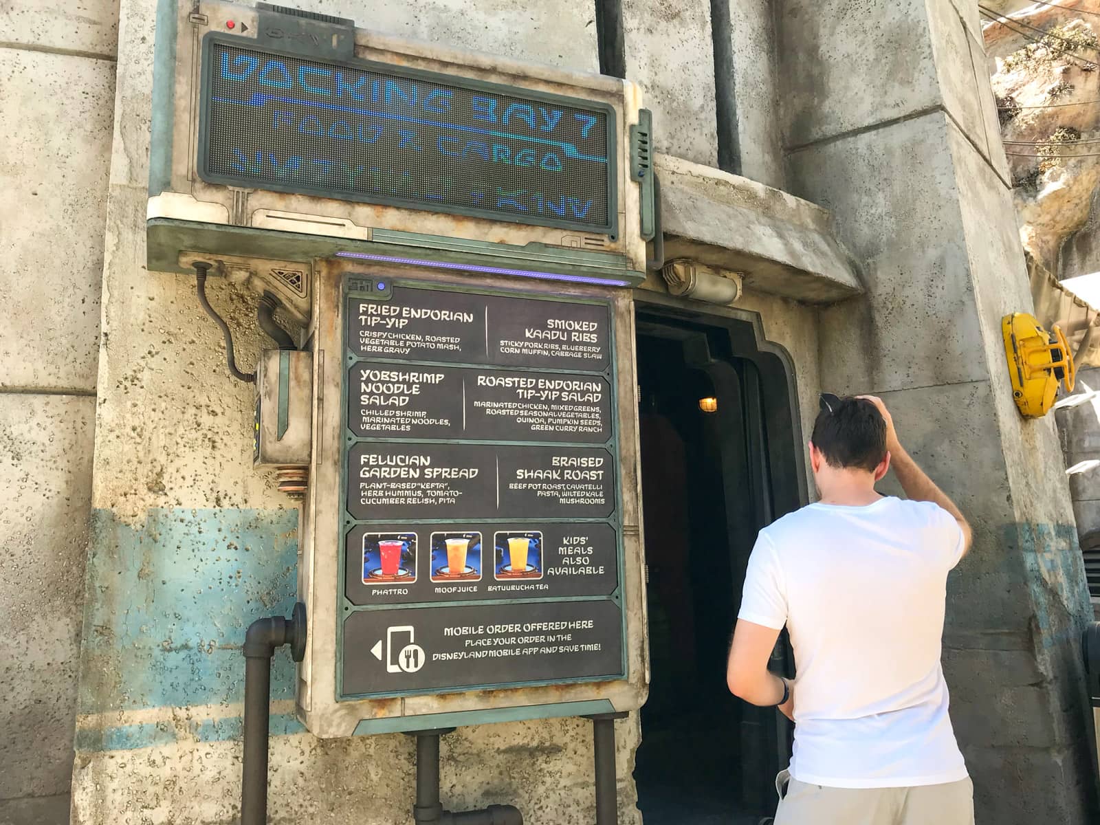 A man walking into the entrance of a cafeteria at a theme park, which is themed to look like a docking bay in Star Wars