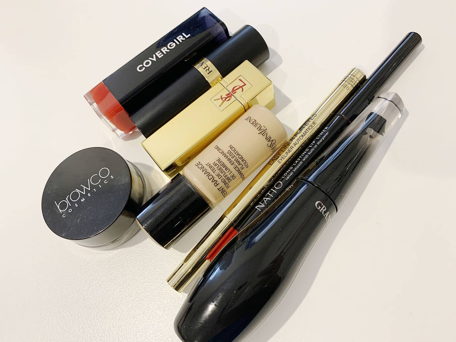 A handful of makeup products on a white surface