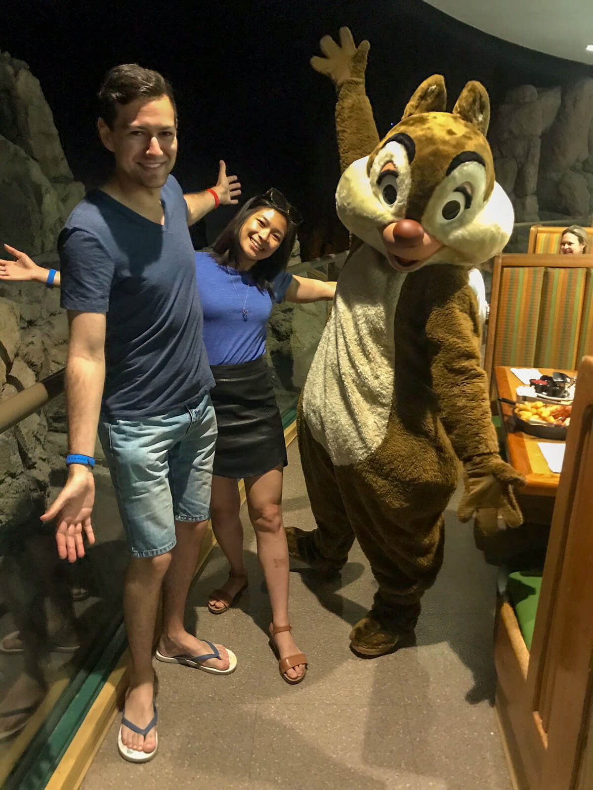 A man and woman with their arms outstretched, alongside someone in a chipmunk costume making the same arm movement