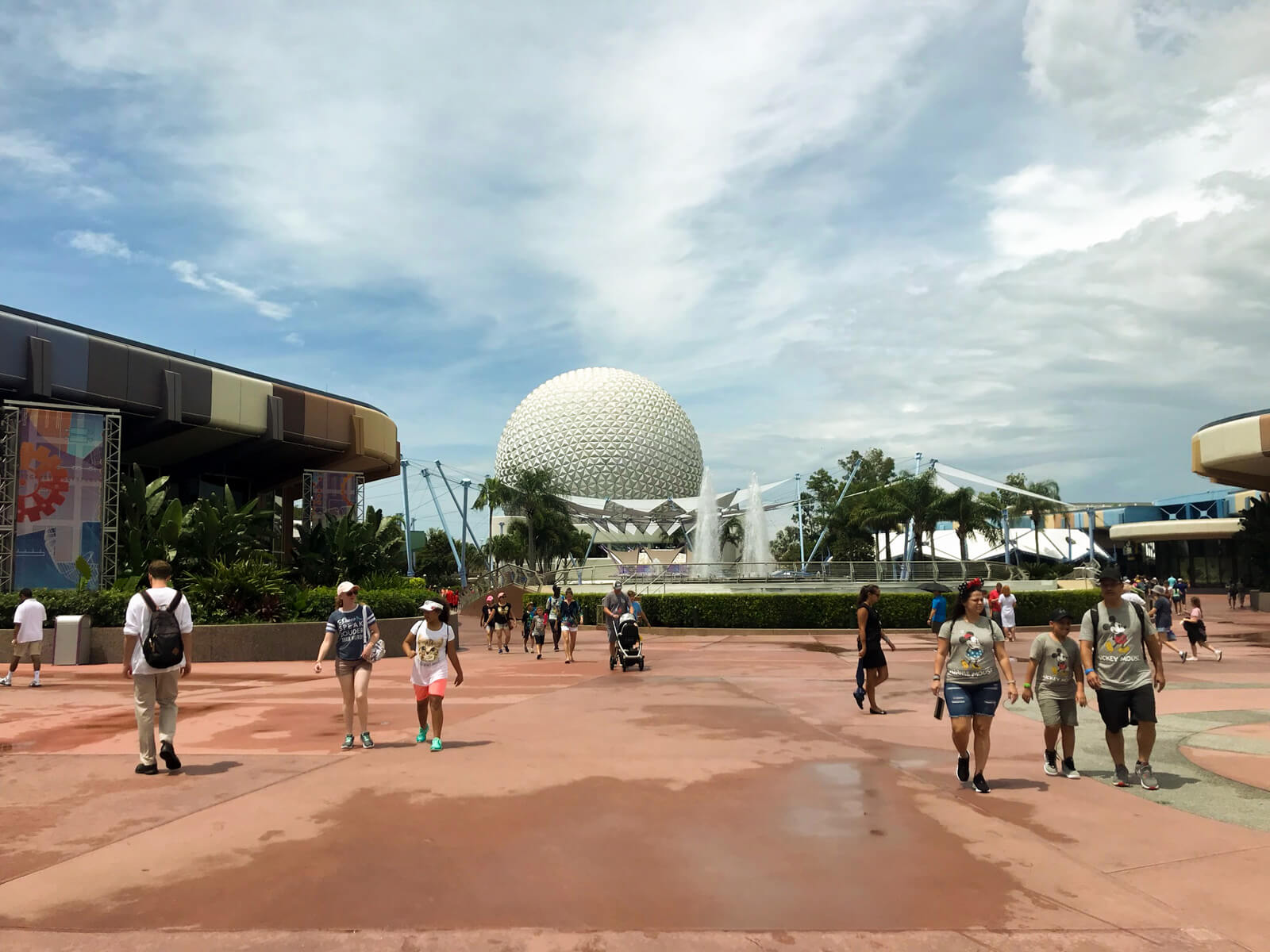 A slightly wet terracotta area, with a water fountain, and in the distance a large globe sculpture with a diamond patterned texture