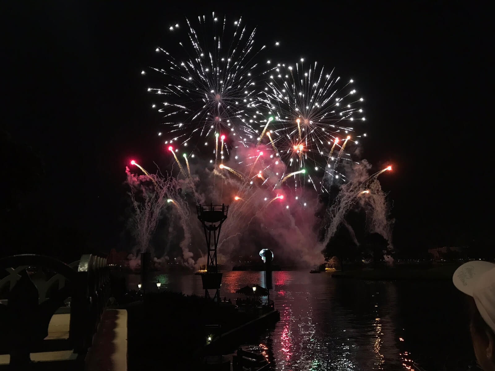 A large display of fireworks and smoke on water on a dark night