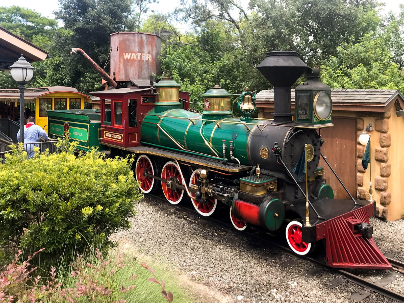 A green and red steam train at a train station.