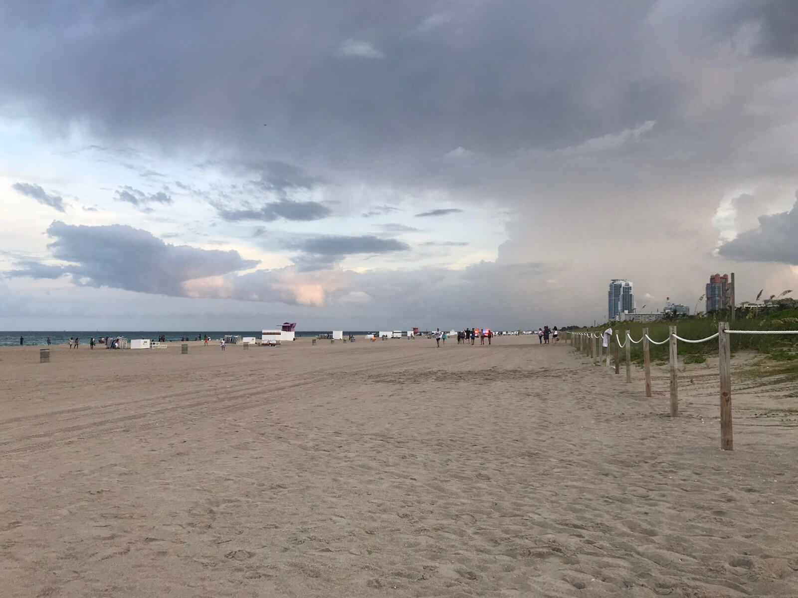 The same beach on the same day, seen further from the shore. The sky has many clouds and it’s close to sunset.