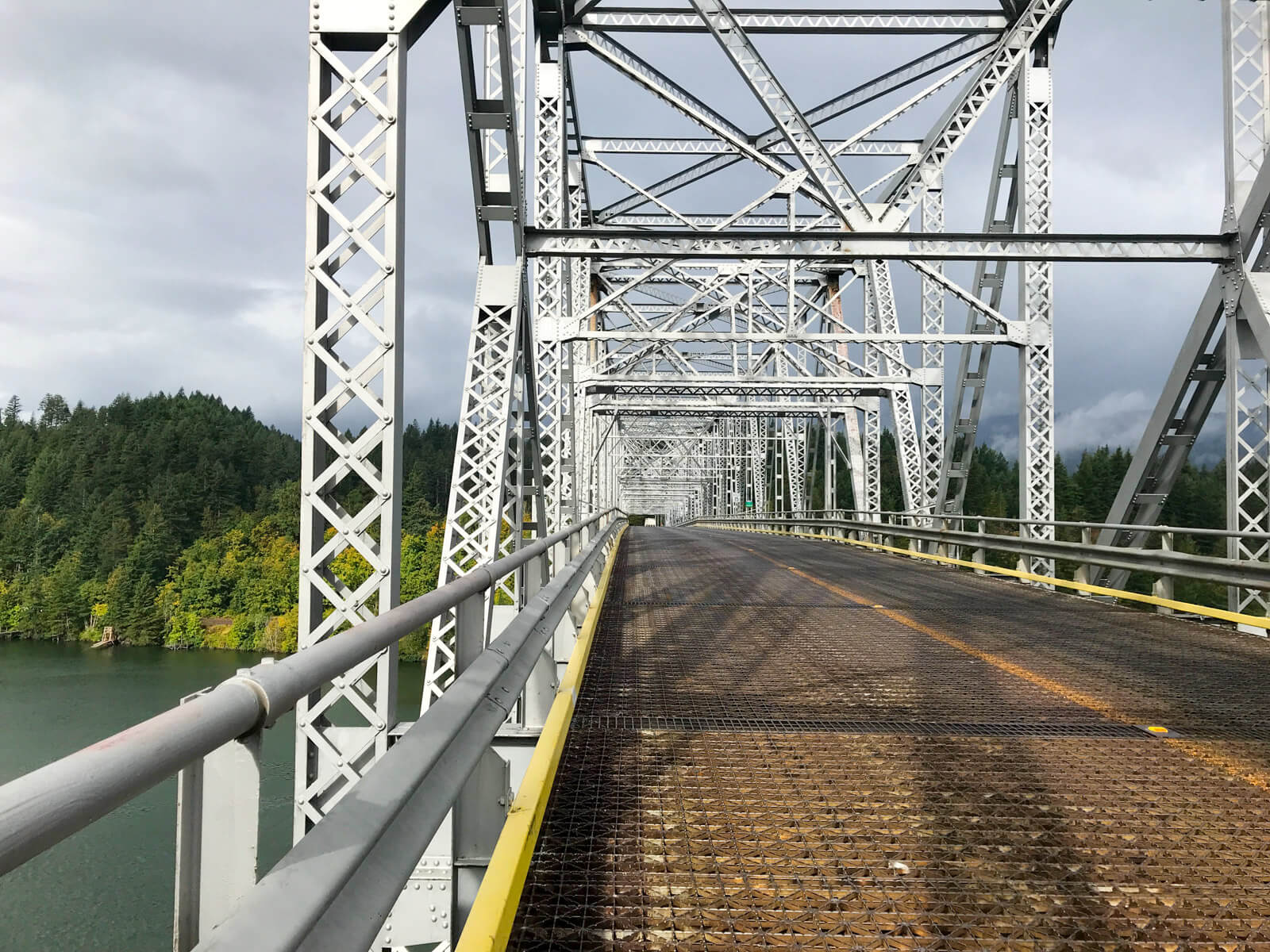 A view taken from a large steel bridge from the left hand side. To the left is a river below.