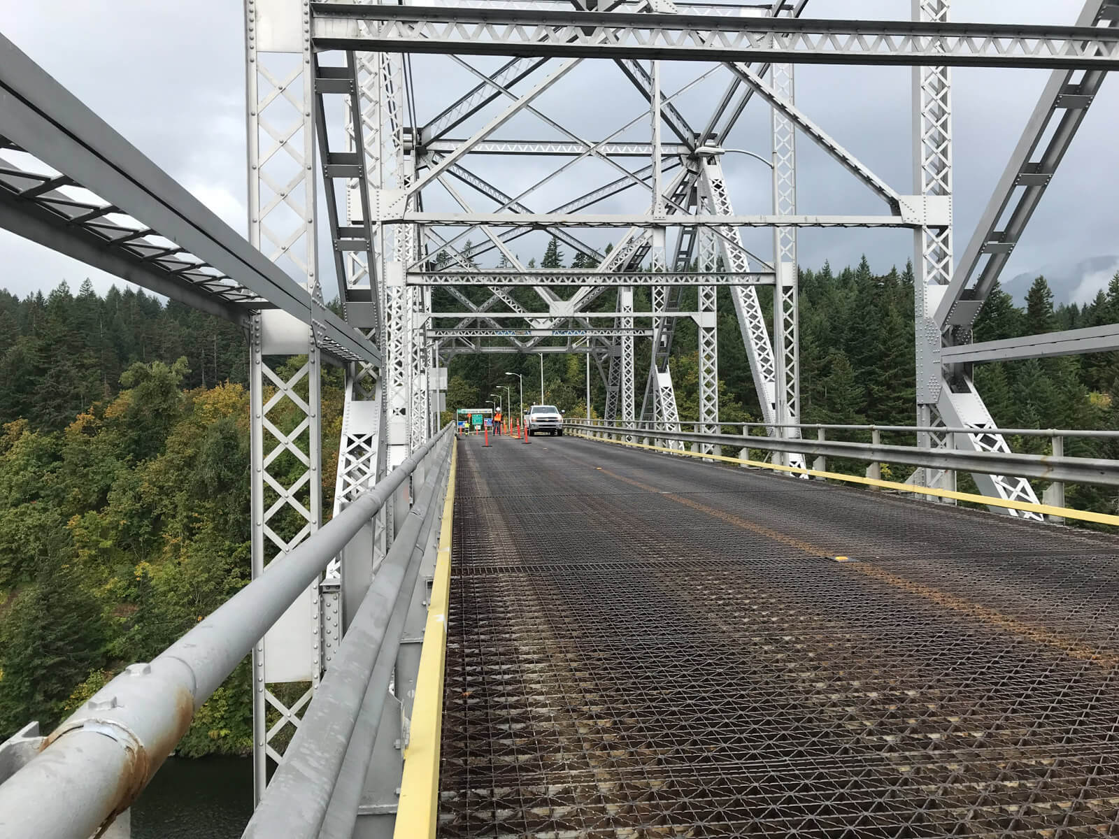 A view taken from a large steel bridge from the left hand side. There is some very light oncoming traffic