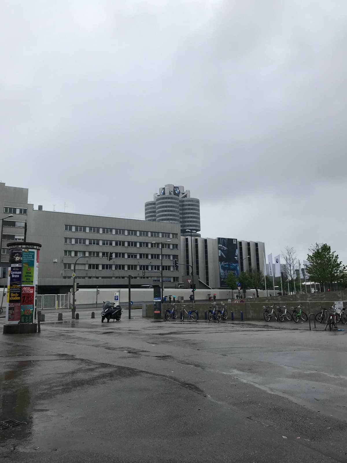 An industrial area with a building consisting of round sections in the distance, with a BMW sign on top. It’s a very cloudy day