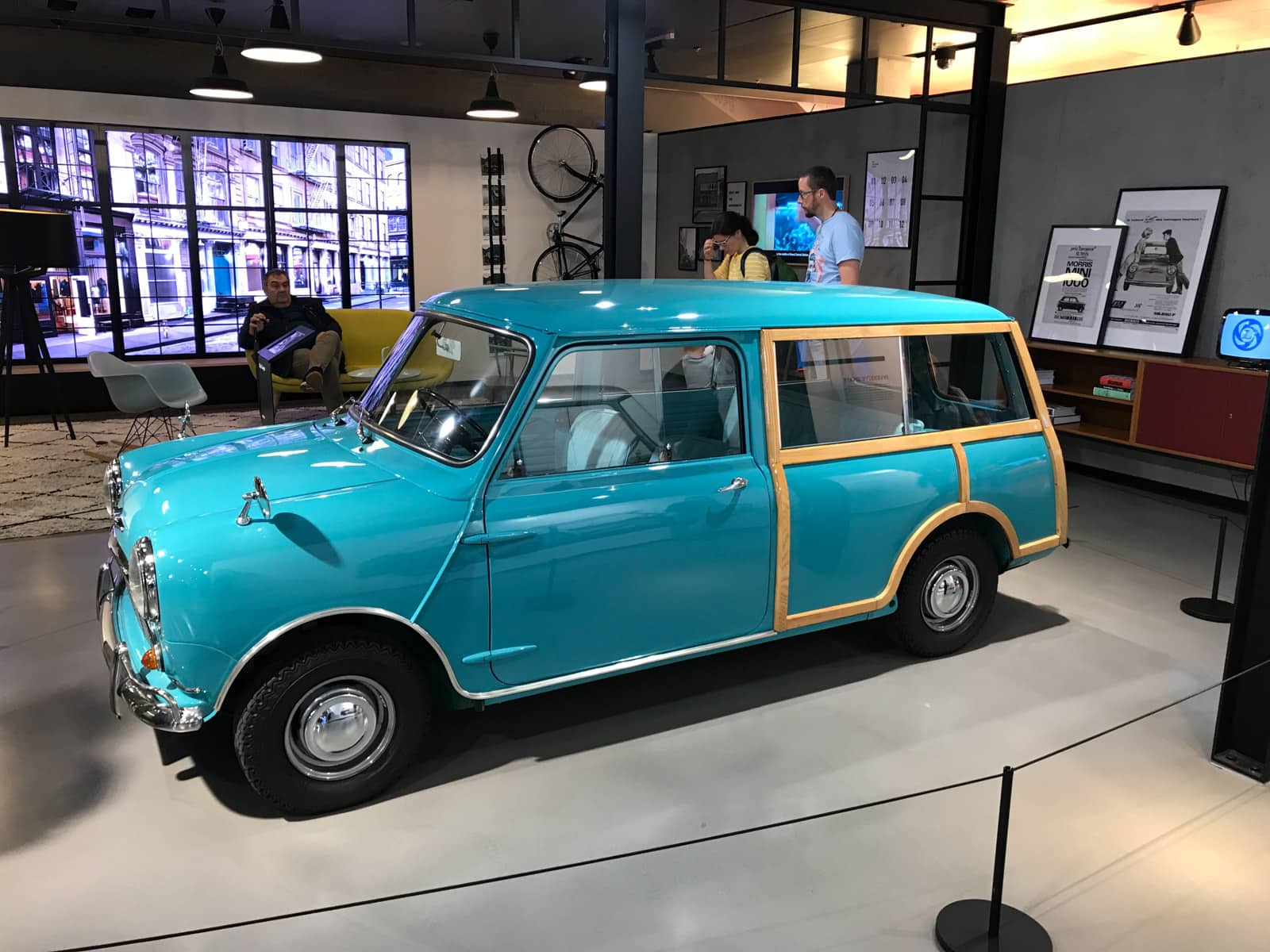 A small light cobalt blue coloured car being showcased indoors