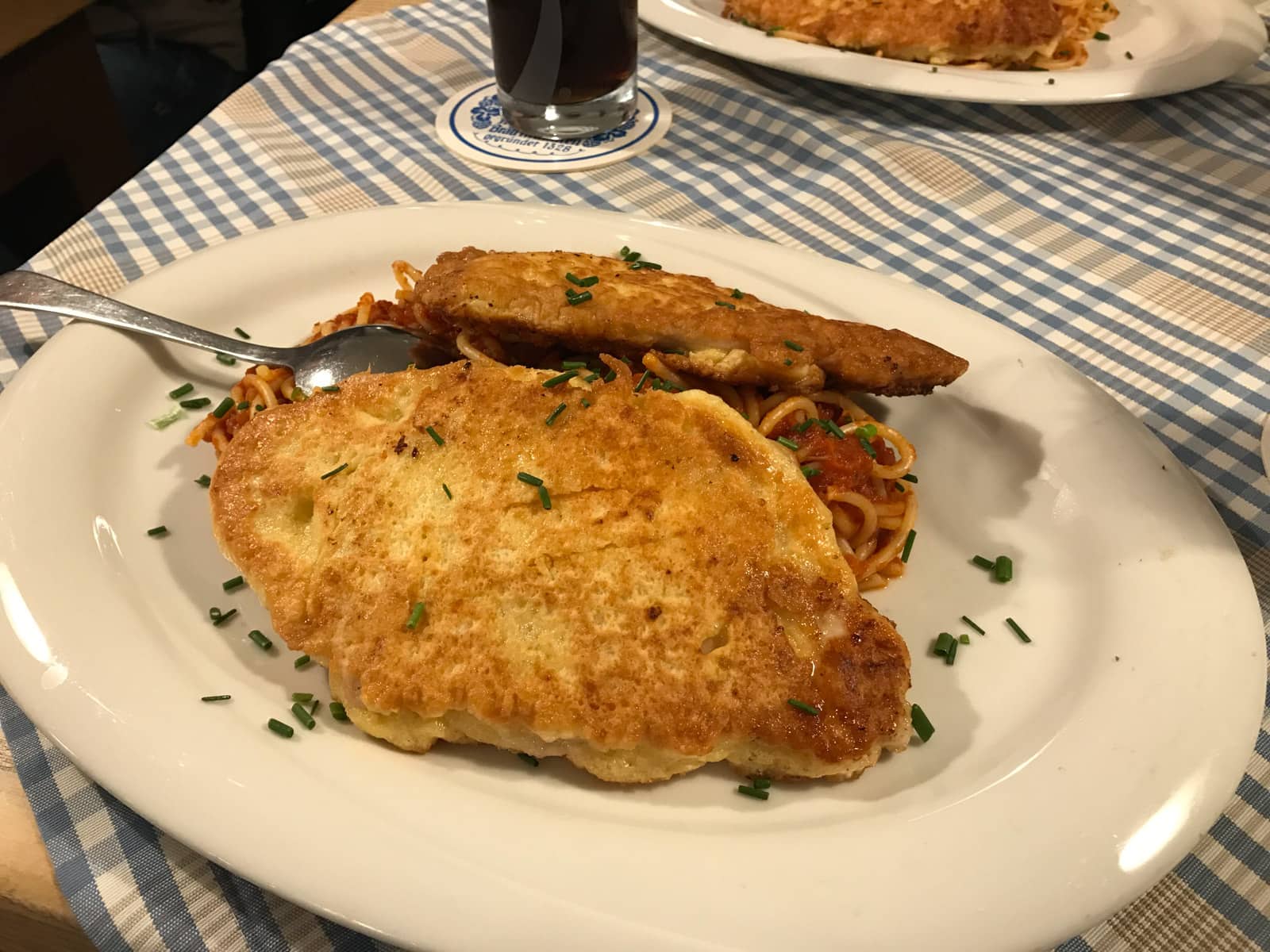 A white plate with turkey schnitzel and spaghetti served on it