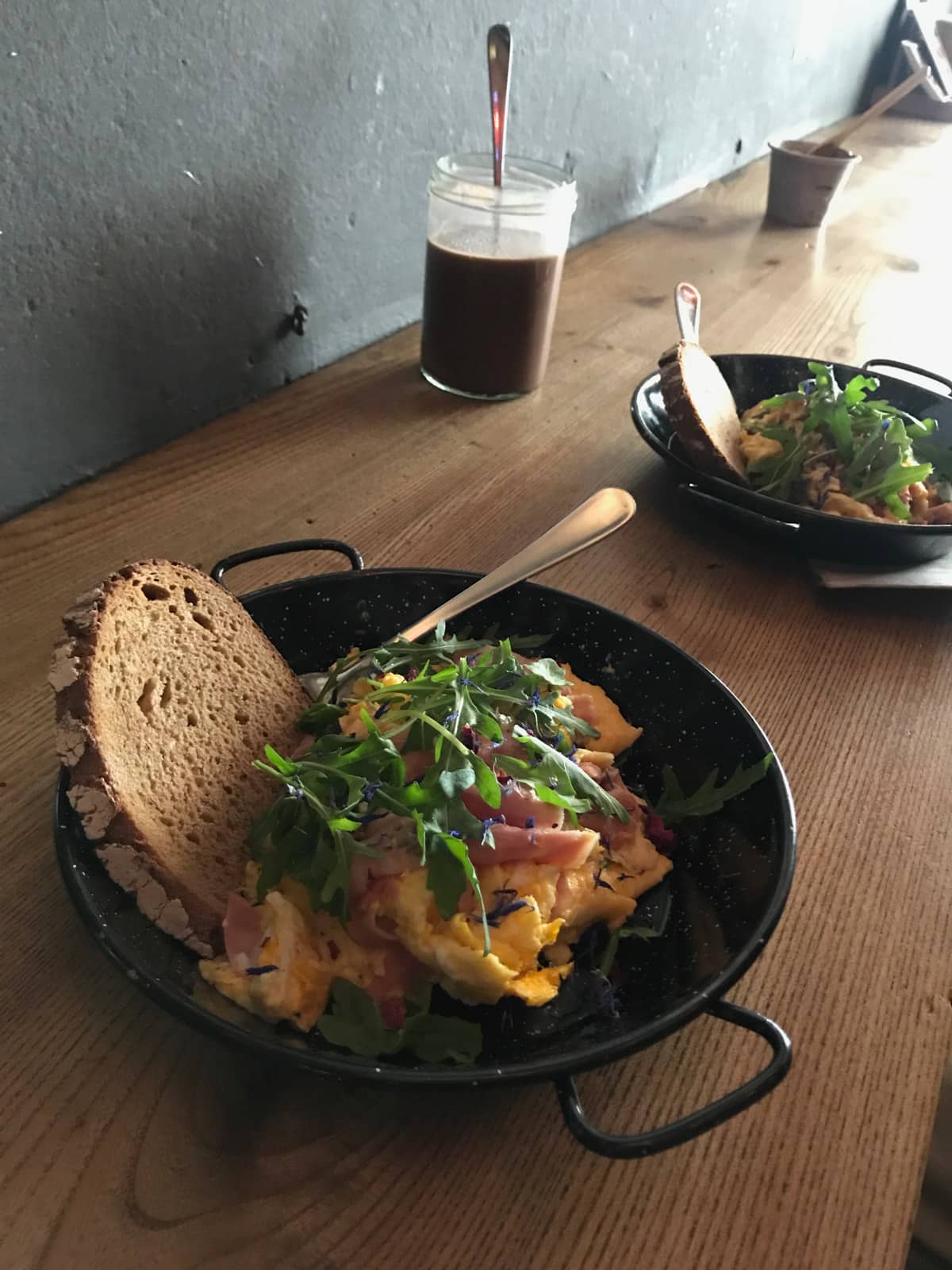 A bench by a wall showing two small black plates of scrambled eggs served