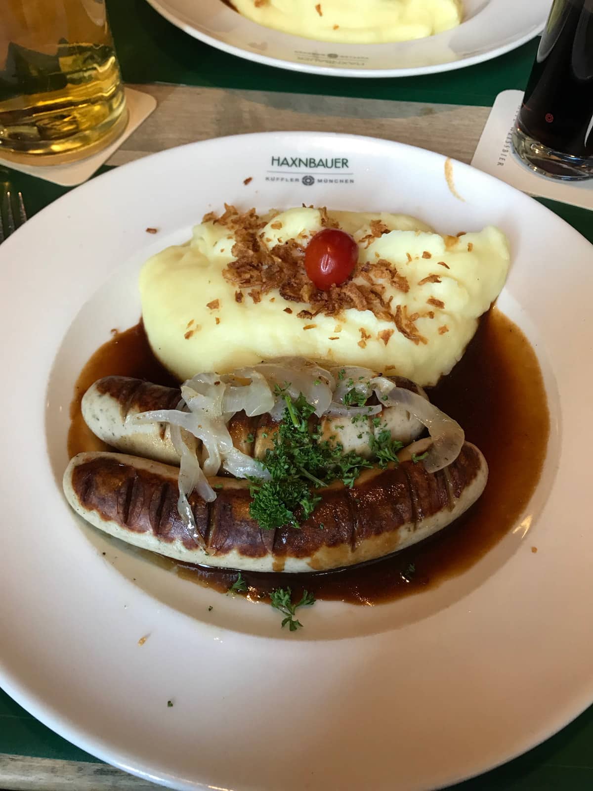 A white plate of two large grilled sausages and mashed potato