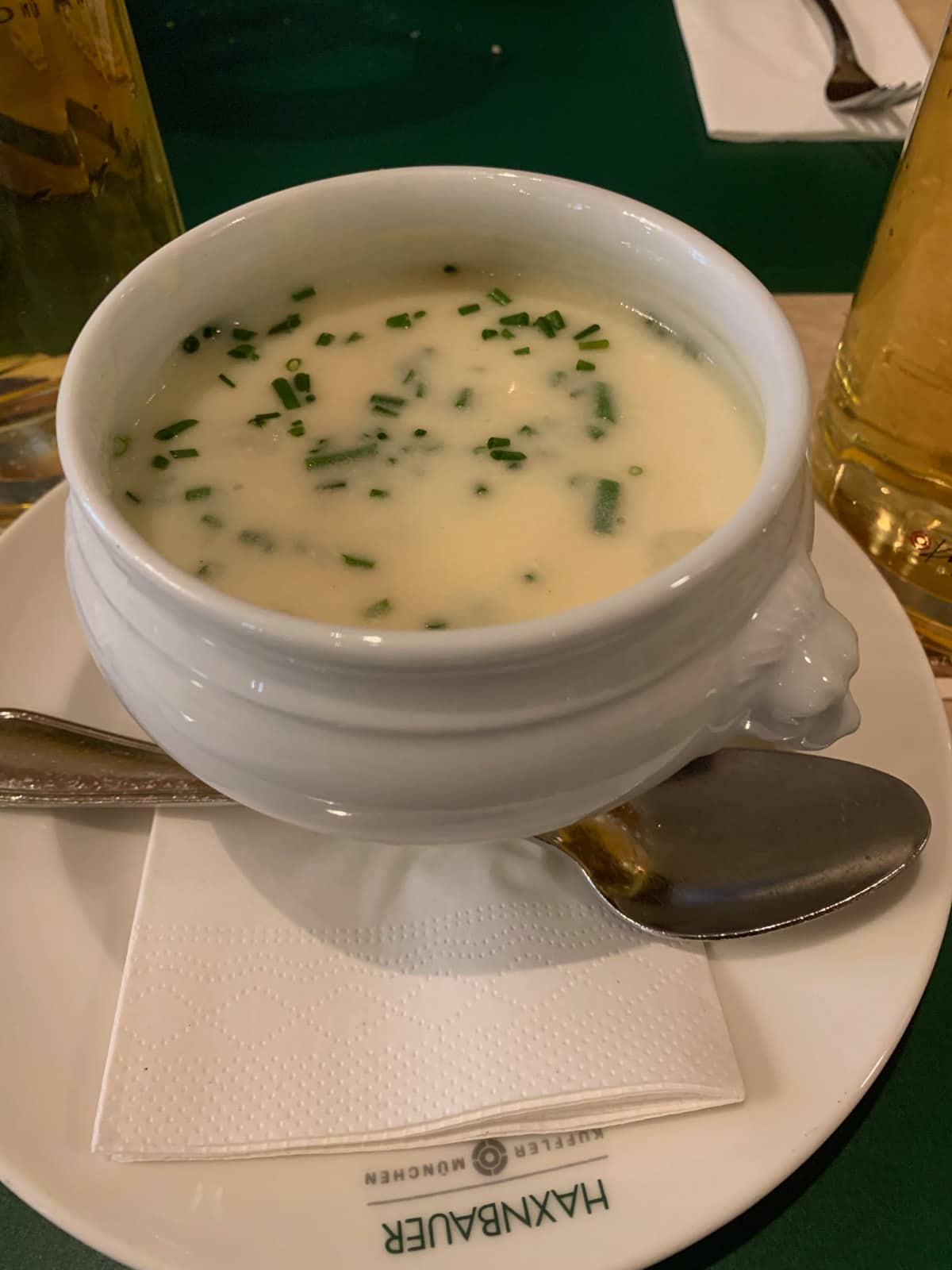 A small white pot of white asparagus soup with chopped leek