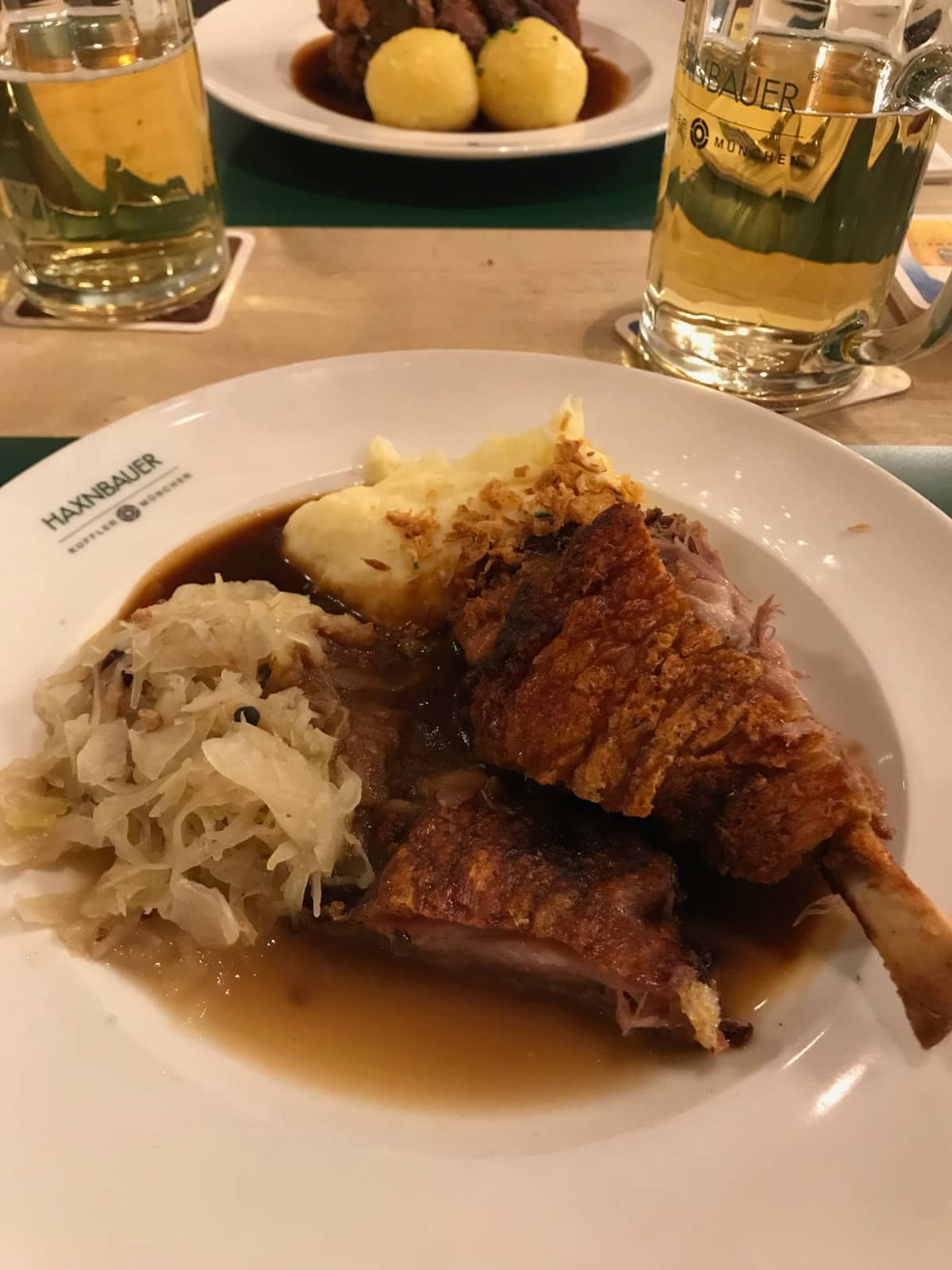 A white plate with pork slices on bone, mashed potato, and white cabbage